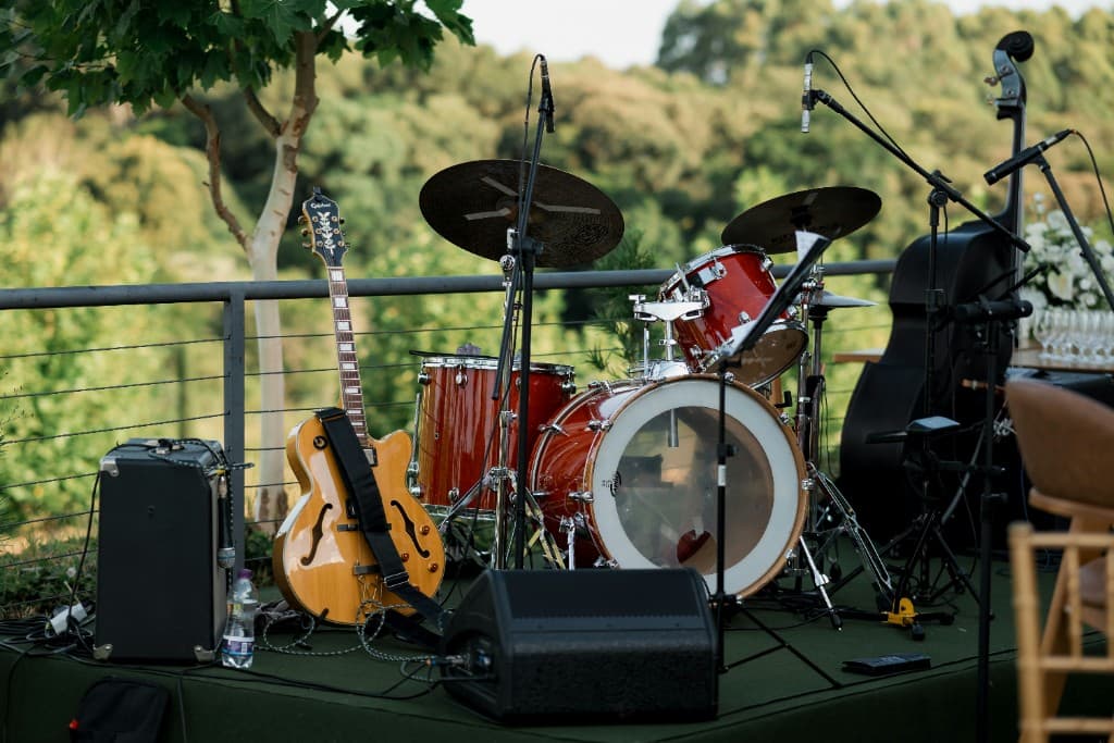 A stage set for a live band, with guitar, drums, microphones, and a double bass.